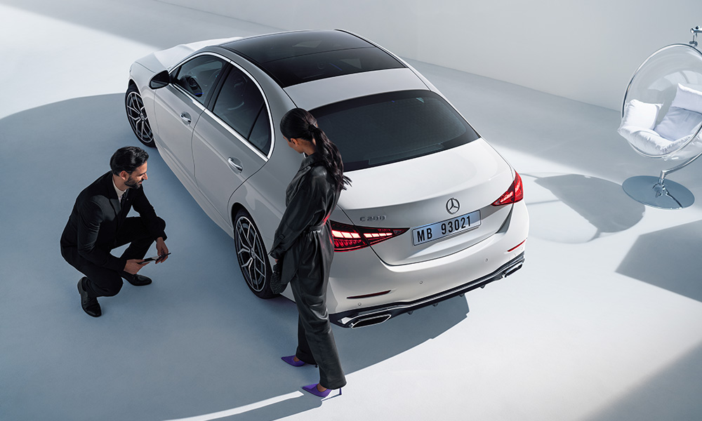 Kundin im Gespräch mit Servicemitarbeiter, begutachten gemeinsam ihren weißen Mercedes-Benz