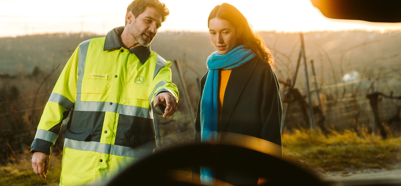 Mercedes-Benz Service 24 h Mitarbeiter im Gespräch mit einer Mercedes Fahrerin vor ihrem GLE der eine Panne hat